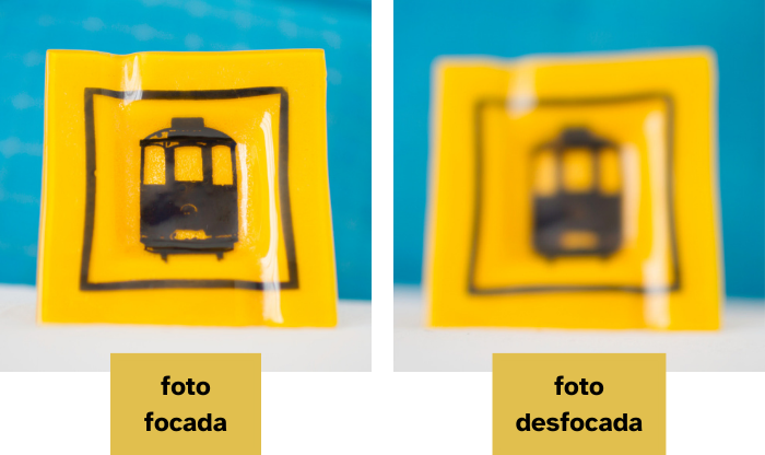 Duas fotos de um efeite quadrado de vidro com desenho de um bonde. Uma das fotos está em foco e a outra está desfocada.