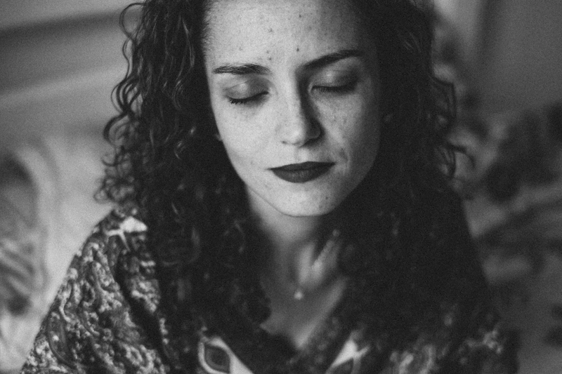 Retrato de mulher com cabelos ondulados de olhos fechados e sorriso suave.