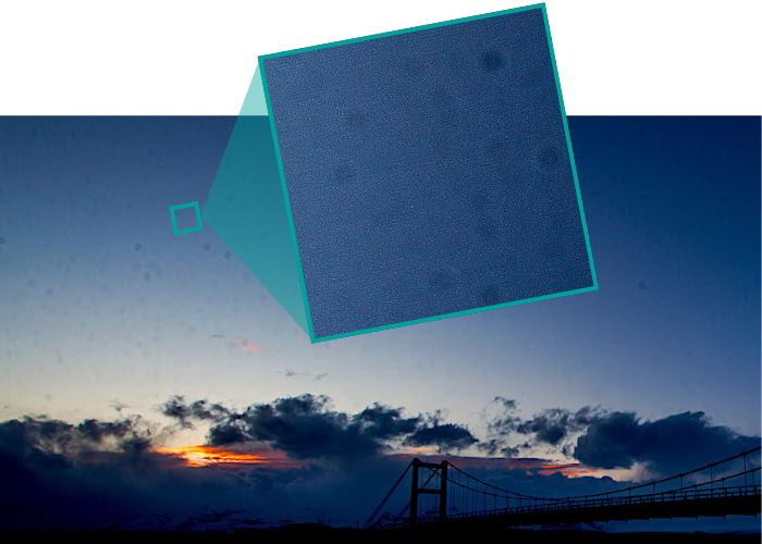 Exemplo de foto de paisagem com um céu azul, pôr do sol e ponte. No céu é possível ver vários pontinhos de sujeira.