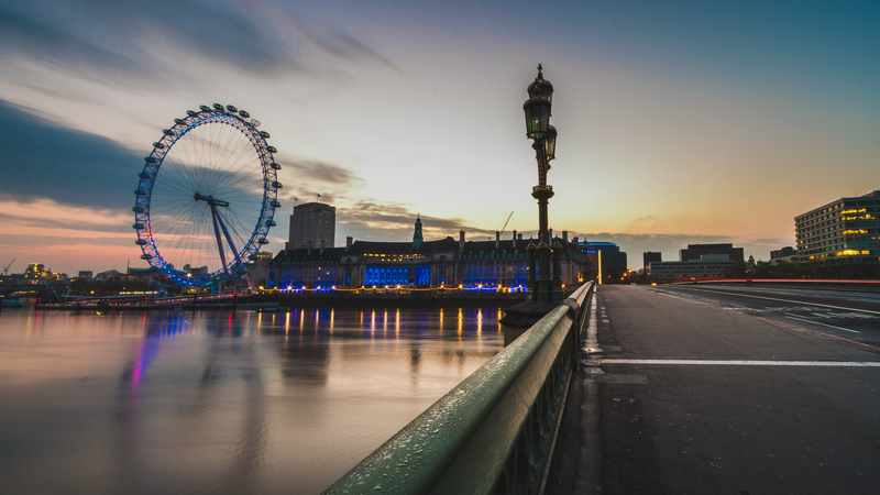 A foto mostra uma ponte vazia, o rio Tâmisa e, ao fundo, a roda gigante London Eye.