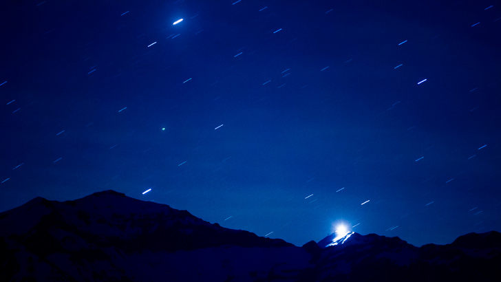 Foto do céu com estrelas sem rastros e montanhas.